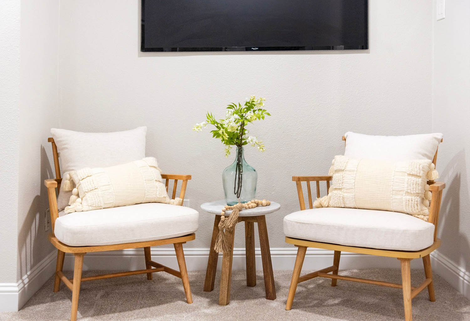 Two cream boucle accent chairs staged with greenery in a Dallas-Fort Worth home by Eleven 11
