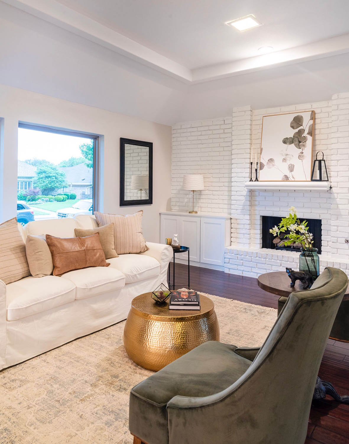 Living room staged with white sofas, fireplace styling, and an olive velvet chair by Eleven 11 Home Staging